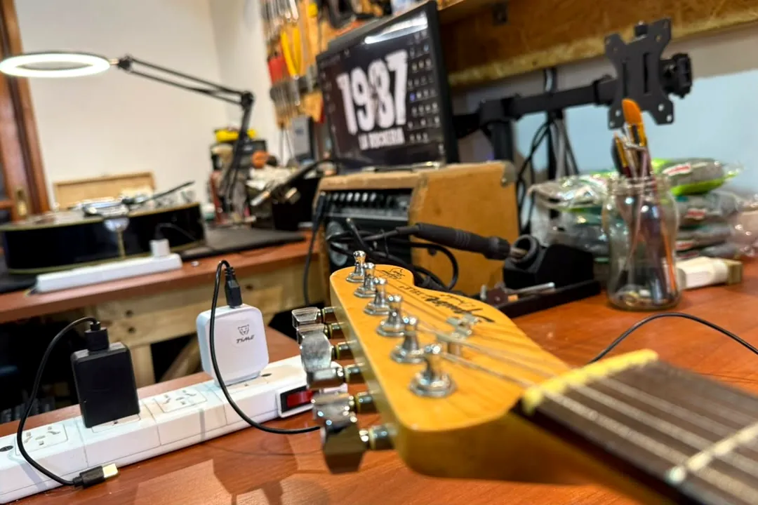 Mástil de guitarra sobre el banco de trabajo bajo la luz de taller durante una calibración